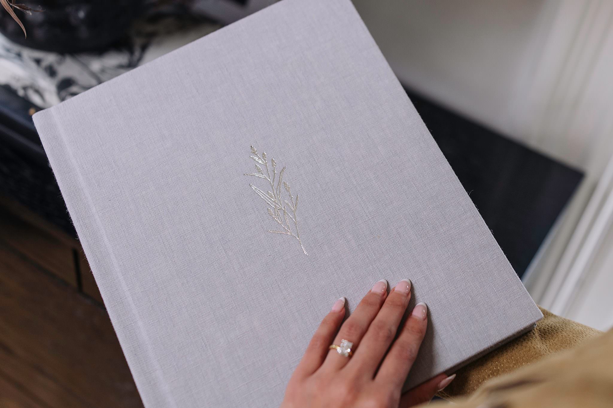 A pale grey linen matted folio album cover with a delicate silver foil floral debossing