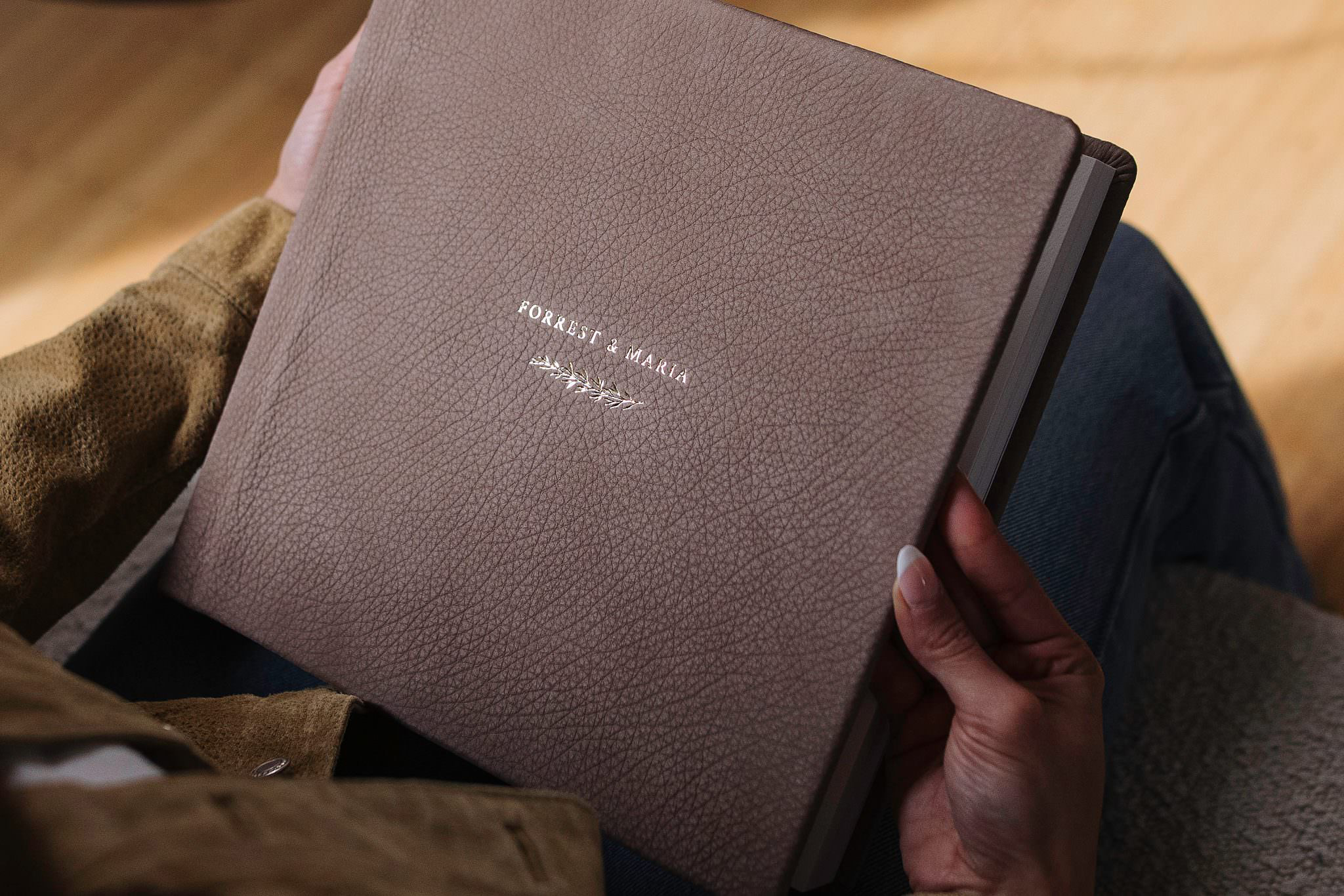 A RedTree leather album held in someone's lap, debossed with names